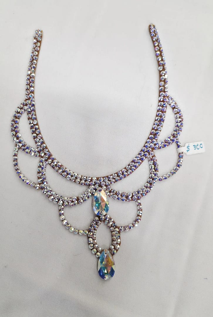 Full flat lay of large crystal ballroom necklace with layered scroll pattern and dual teardrop crystals
