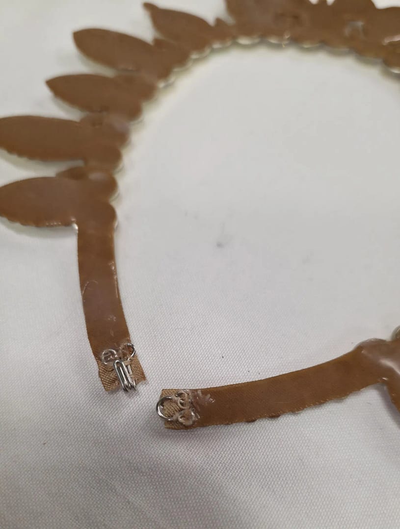 Back construction of large stones ballroom necklace showing silicone backing and secure clasp for performance fit